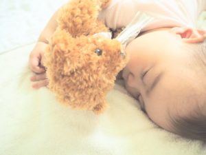 クマのぬいぐるみと寝る赤ちゃん